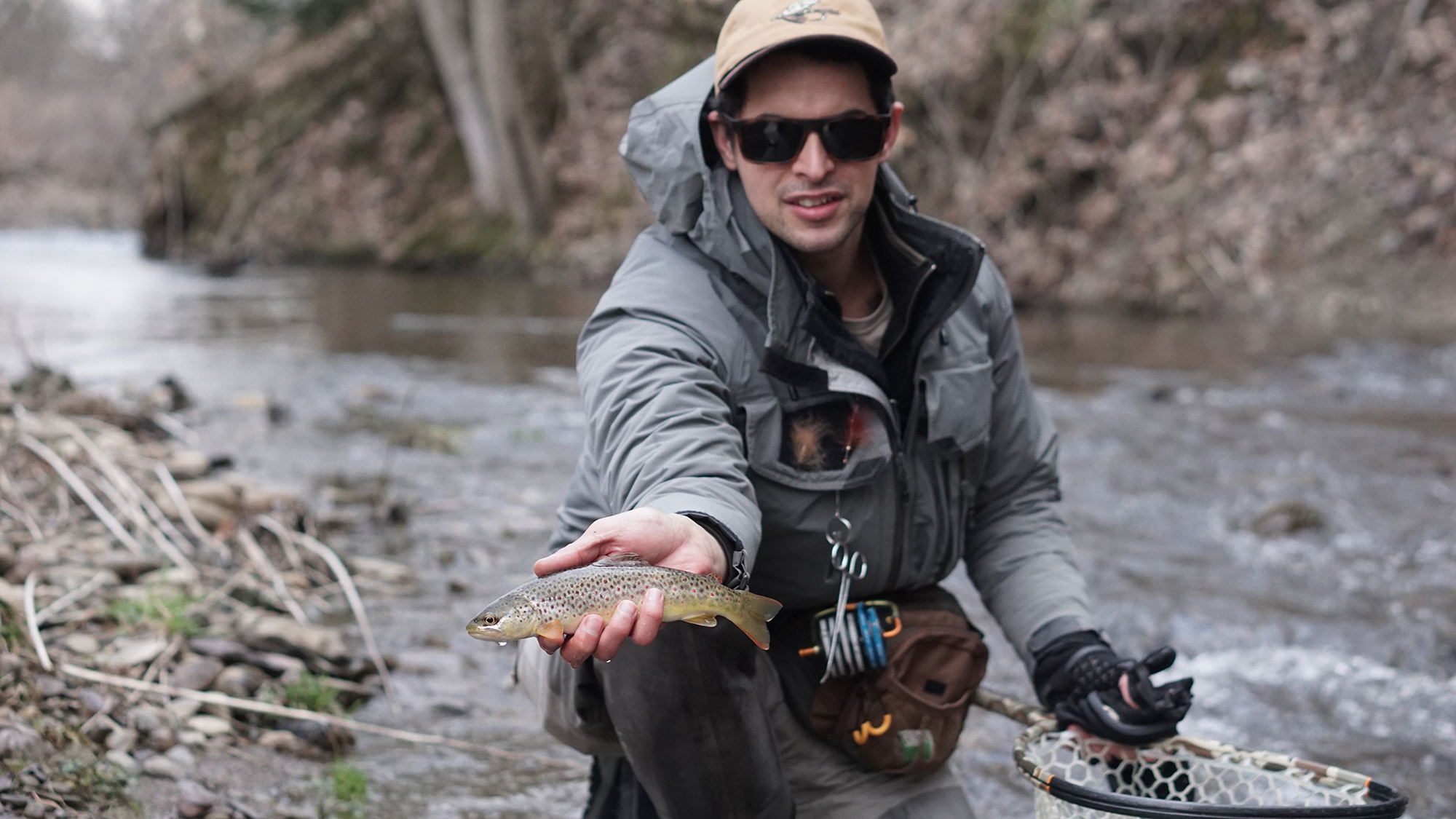 A fly fisherman holds a brown trout