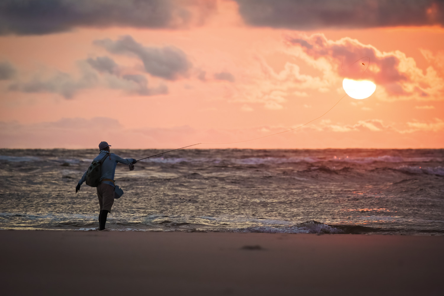 Tim Lewis casts his 12-weight into the Atlantic Ocean as the sun sets.